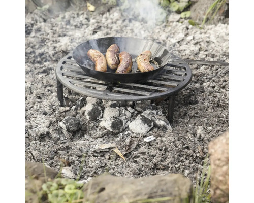 Klobása na smažení na pánvi na grilu nad táborákem
