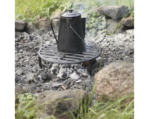 Černá varná konvice na grilovací mřížce nad dřevěným uhlím