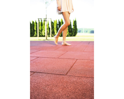 Gumové zámkové dlaždice na terase s ženou, která po nich chodí naboso.