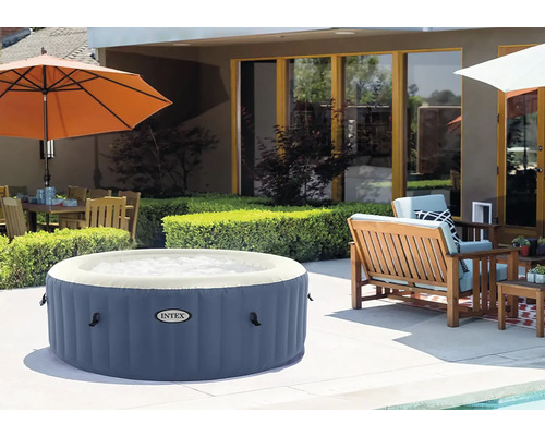 Nafukovací vířivka v zahradě s posezením a slunečníkem.