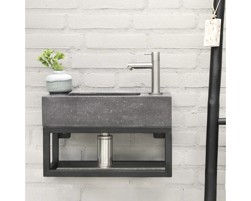 Umyvadlo s baterií, rostlinou a držákem na ručníky před cihlovou zdí