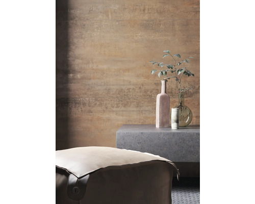 Pohled do místnosti s pufem, odkládacím stolkem a dekorativními předměty před vzorovanou stěnou