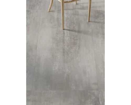 Dlažba s betonovým vzhledem a nohy židle v popředí.