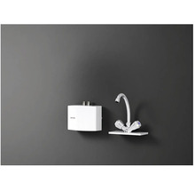 Elektrický ohřívač vody vedle kohoutku na zdi