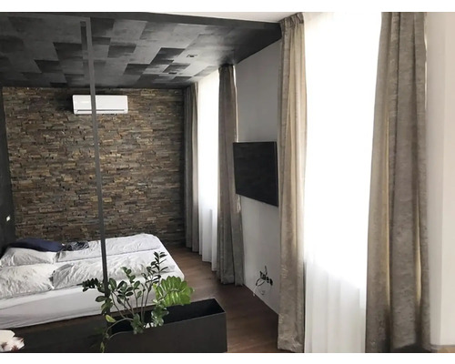 Ložnice s kamennou zdí, manželskou postelí a závěsy