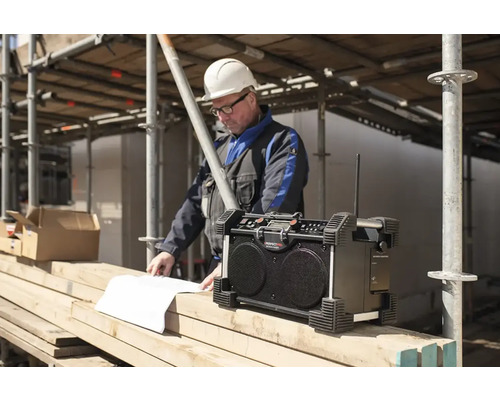 Stavební rádio se stavebním dělníkem, který se dívá na plány