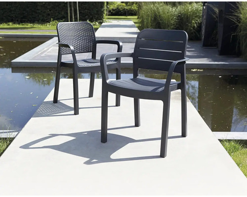 Dvě šedé plastové zahradní židle s područkami stojí venku