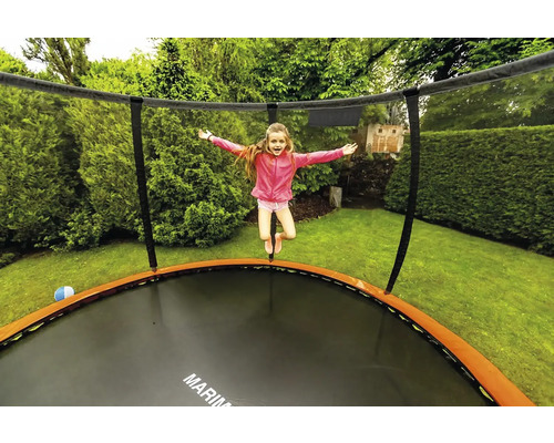 Dívka skáče na zahradní trampolíně se sítí