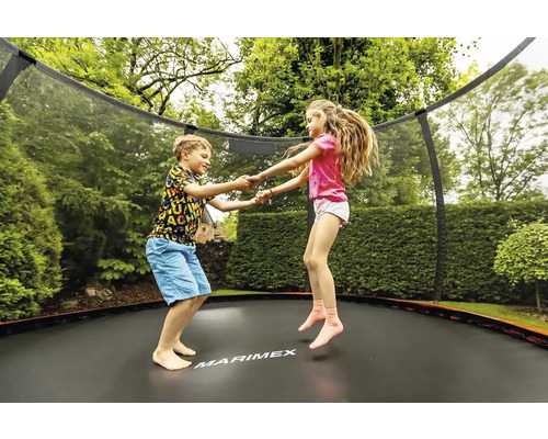 Dvě děti skákají na zahradní trampolíně s ochrannou sítí.