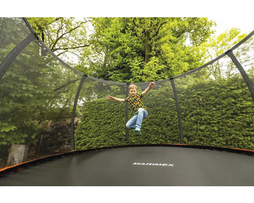 Chlapec skáče na zahradní trampolíně Marimex s ochrannou sítí.