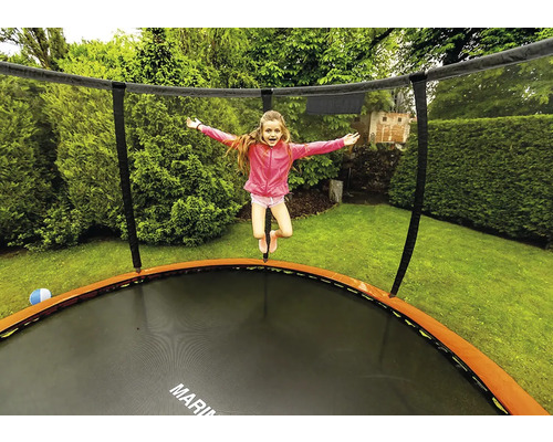 Dívka skáče na zahradní trampolíně se sítí