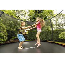 Dvě děti skákají na zahradní trampolíně se sítí
