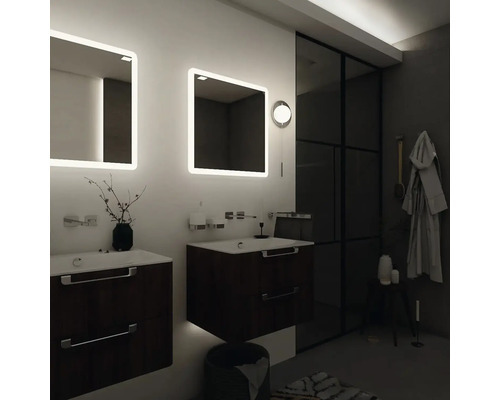 Koupelna se dvěma umyvadly, osvětlenými zrcadly a tmavým sprchovým koutem