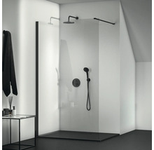 Sprchový kout v úrovni podlahy se skleněnou stěnou a černými armaturami v koupelně.