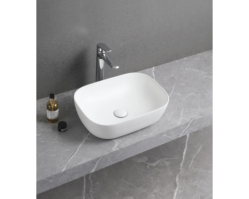 Keramické umyvadlo na desce s vodovodní baterií na polici