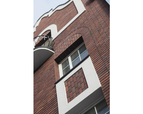 Fasáda budovy s cihlovou zdí, okny a balkonem