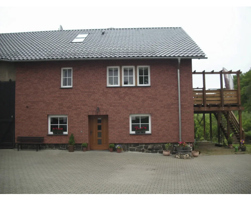 Pohled na dvoupatrový dům s taškovou střechou a dřevěnou terasou