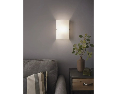 Skleněná nástěnná lampa vedle pohovky a nočního stolku v obývacím pokoji.