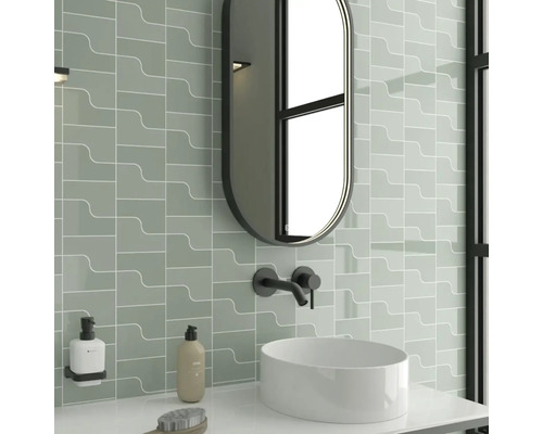 Moderní koupelna se šedozelenými obklady, oválným zrcadlem a umyvadlem na desku