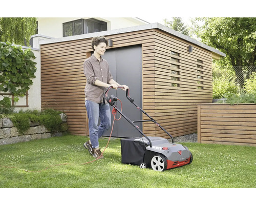 Žena používá elektrickou sekačku na trávu na trávníku