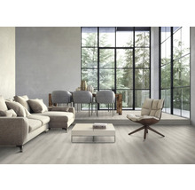 Světlý obývací pokoj s pohovkou, židlemi, stolem a velkým oknem s výhledem na stromy.