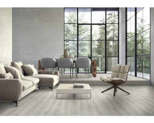 Světlý obývací pokoj s pohovkou, židlemi, stolem a velkým oknem s výhledem na stromy.