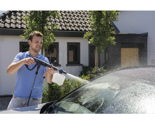 Muž používá k mytí auta tlakovou myčku.