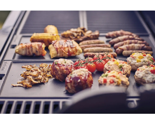 Různé potraviny, jako jsou klobásy, slanina, rajčata a plněné žampiony na grilu.