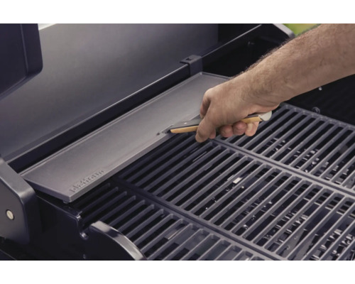 Muž pokládá grilovací desku na grilovací rošt.