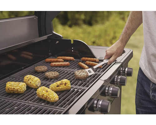 Plynový gril s klobásami, kukuřičnými klasy a hamburgery na grilovací mřížce