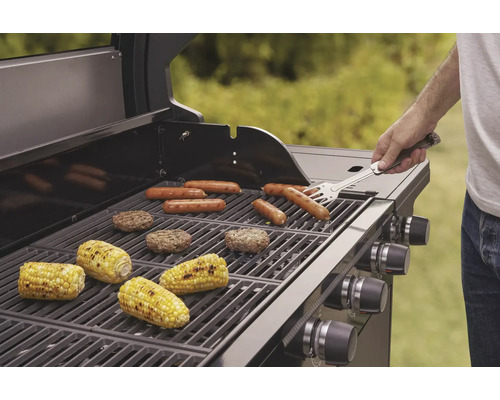 Gril s klobásami, hamburgery a kukuřičnými klasy na grilovací mřížce