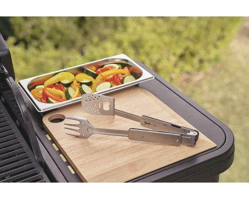 Zelenina v misce, grilovací kleště a krájecí deska na grilu