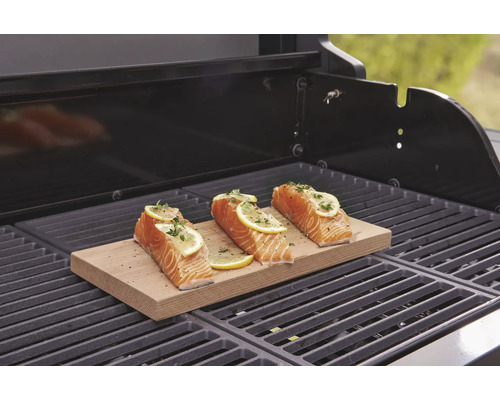 Tři filety lososa s citronem na dřevěném prkénku na grilu