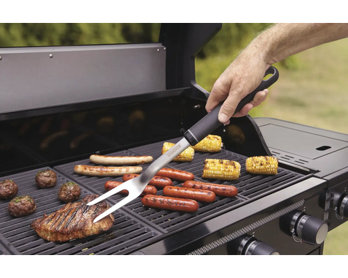 Osoba používá grilovací vidličku na grilu s různými potravinami.