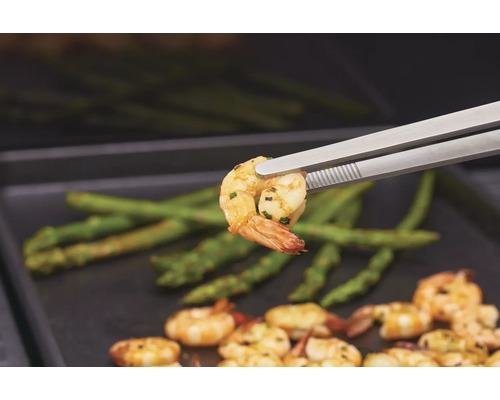 Grilované krevety s chřestem, podávané s grilovacími kleštěmi.