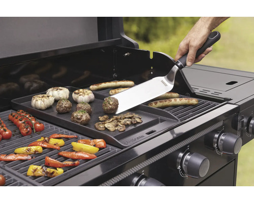 Gril s grilovací deskou, grilovacími nástroji a různými potravinami, jako je zelenina, klobásy a masové kuličky