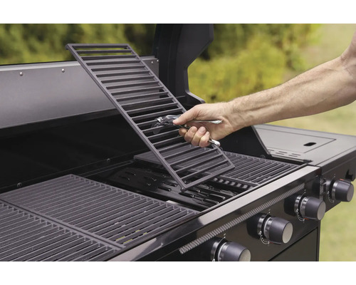 Osoba vkládá grilovací rošt do plynového grilu.