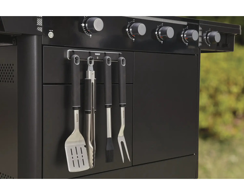 Detail černého plynového grilu s grilovacím náčiním