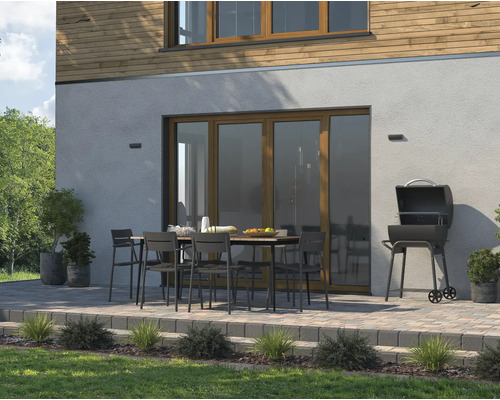 Venkovní scéna s grilem, zahradním stolem a židlemi na terase před domem