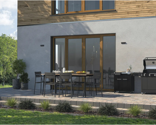 Venkovní prostor se zahradním stolem, židlemi a grilem na terase vedle domu.