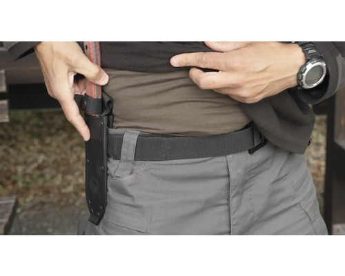 Osoba připevňuje pouzdro na sekeru k opasku.