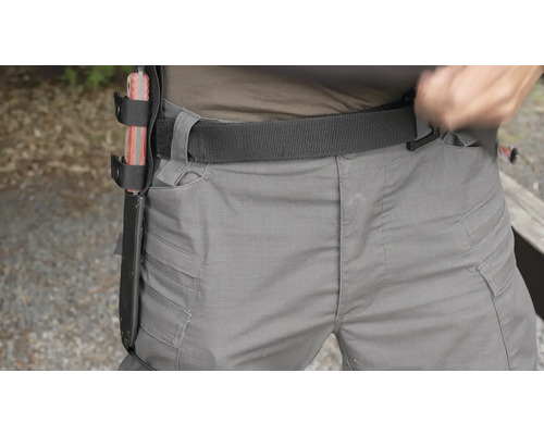 Osoba s pouzdrem na nůž na opasku a pracovní kalhoty.