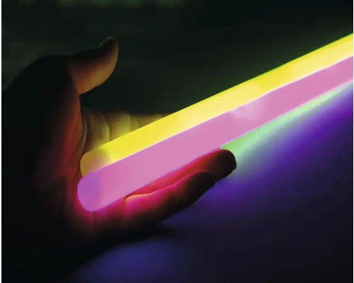 Osoba drží svítící světelné tyčinky