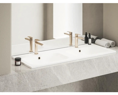 Dvojité umyvadlo s bateriemi, kosmetickými produkty a ručníky v koupelně.