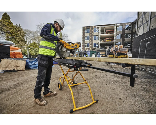 Stavební dělník řeže dřevěnou desku venku pokosovou pilou.