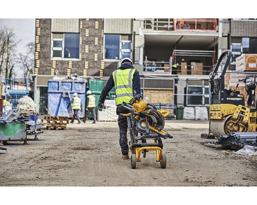 Stavební dělník přepravuje pokosovou pilu na staveništi