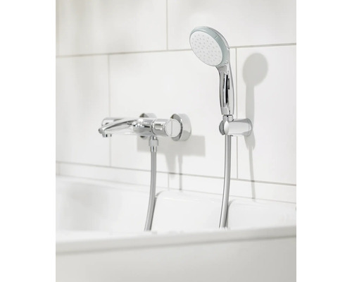 Nástěnná sprchová baterie a ruční sprcha v koupelně.