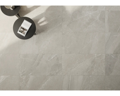 Světlá podlahová dlažba s mramorovým vzhledem položená, se stolem a knihou.