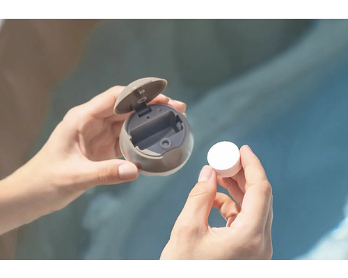 Osoba drží tabletu bazénové chemie a dávkovací plovák