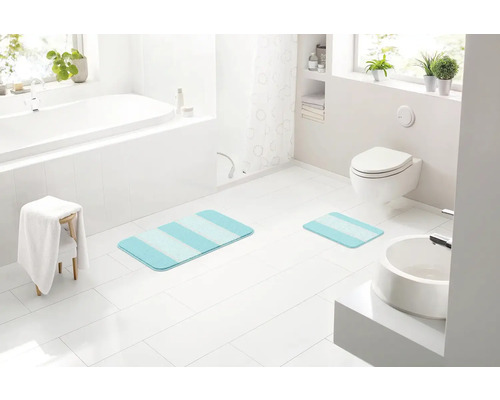 Moderní koupelna s vanou, toaletou, umyvadlem a pruhovanými koupelnovými předložkami